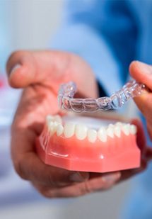 Dentist placing clear aligners over model teeth