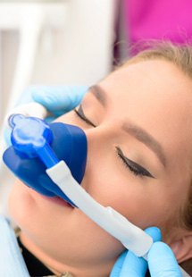 Woman with eyes closed and blue nitrous oxide mask over nose